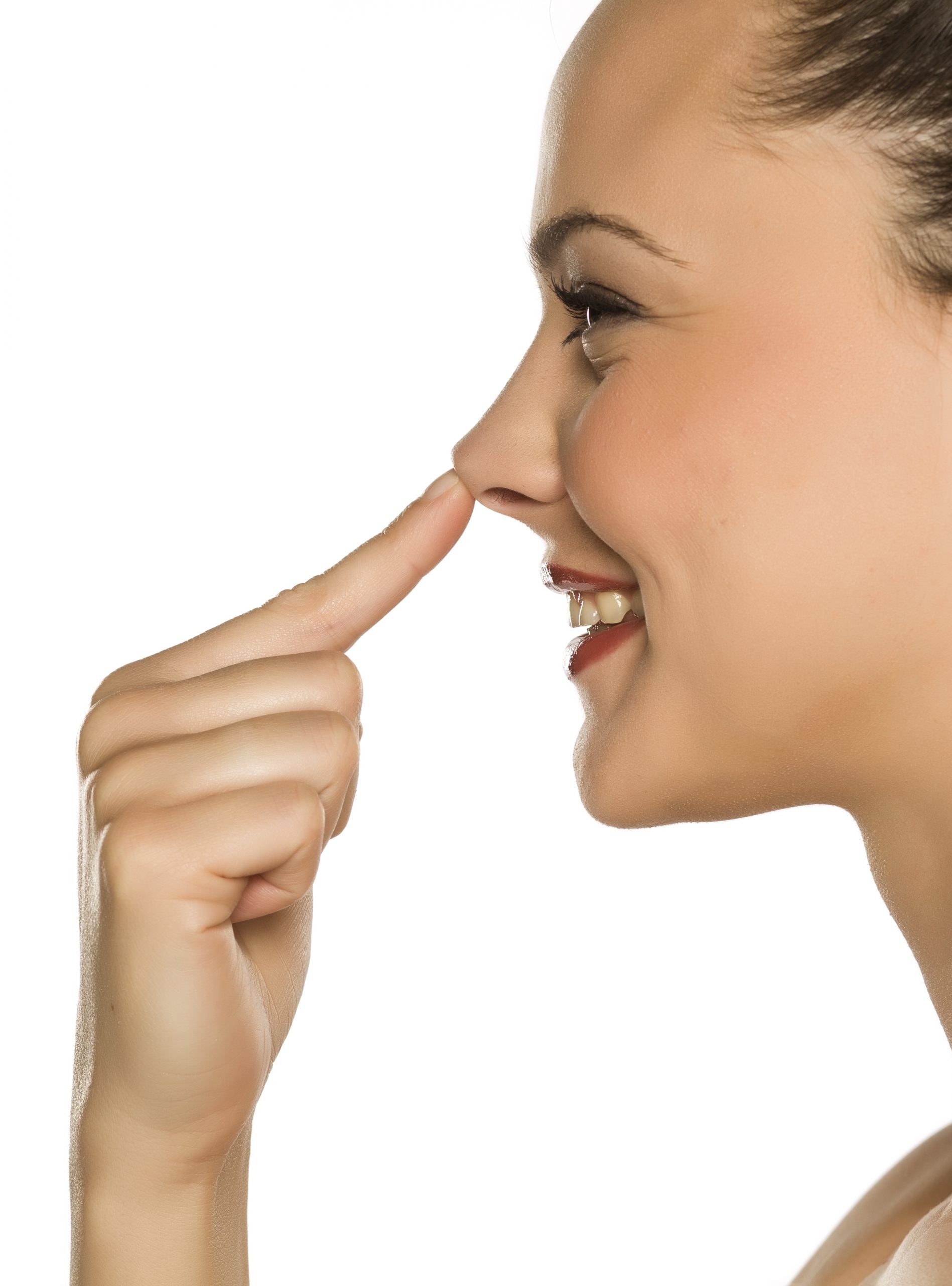 young happy woman touches her nose with her finger on a white ba